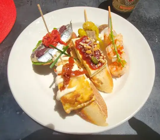 photo of five pinchos on a plate.  The center one, with a rectangle of white and a red sauce, is the one I'm asking about