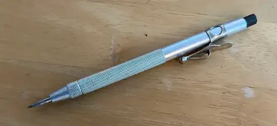 Photo of a scriber on a wooden table.  It's a pencil-shaped metal holder with a sharp tip.  Photo taken by me.