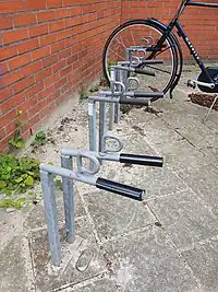 An example of a common type of front-wheel-only bike stand in the Netherlands. No danger of wheel bending, with a loop for attaching a lock.