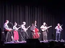 Sutton (second from right) playing guitar in 2022, in support of Bela Fleck's album My Bluegrass Heart.