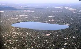 An aerial view of Lake Harriet surrounded by parkland and mostly low residential buildings