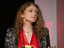 Woman with mid-length dark curly hair looks off to the right