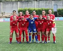 Lineup of eleven players of the Lebanon women's national under-20 football team. The outfield players are wearing red kits, and the goalkeeper is wearing a blue kit.