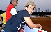 Hooda leaning on the fence of an Equestrian ground.