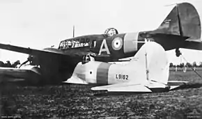 Rear three-quarter view of two military monoplanes lying wheels up on a field, one atop the other