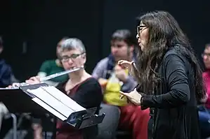 musical performance showing conductor, flutist, other musicians