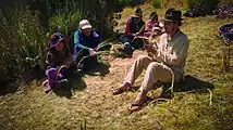 Volunteer learning how to build a hand-made rope out of grass